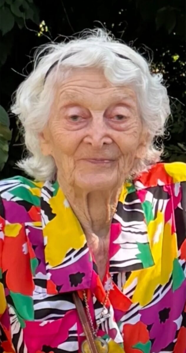 Naomi A. Reich, smiling, with white hair and a vividly colorful patterned blouse